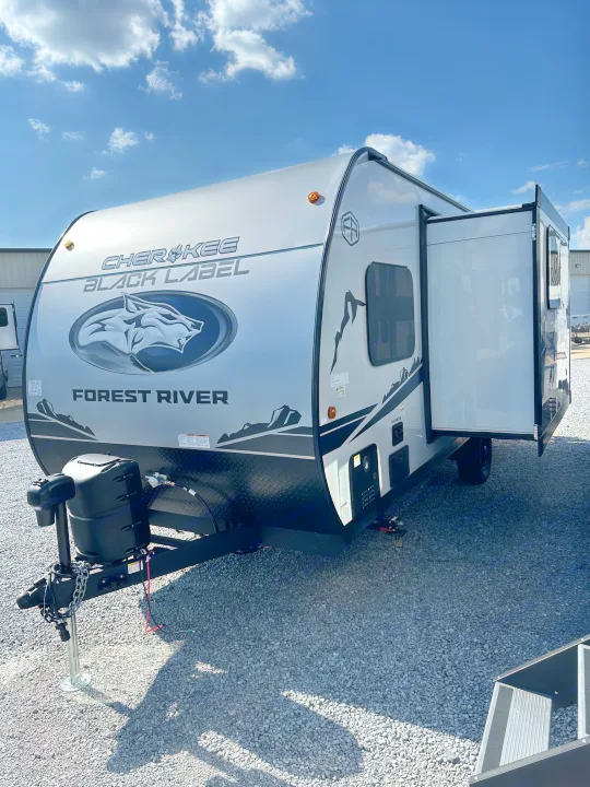 New Forest River Cherokee Black Label travel trailer, ideal for an rv rental, with a slide-out, parked on gravel under blue sky.. Forest River Cherokee Wolf Pup 2025