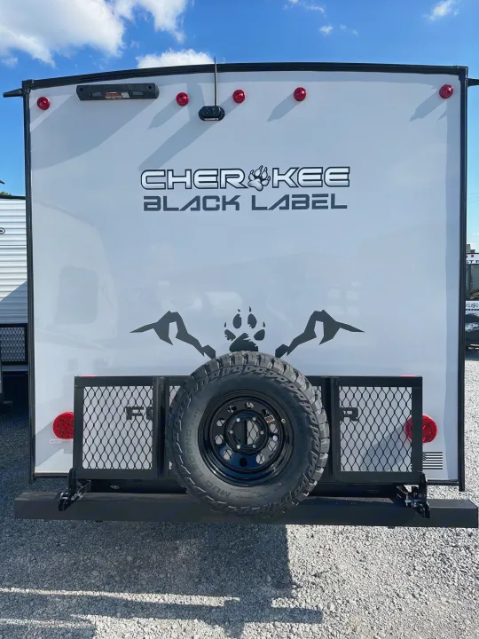 Rear of a white Cherokee Black Label travel trailer with a spare tire mounted, ready for your RV rental adventure.. Forest River Cherokee Wolf Pup 2025