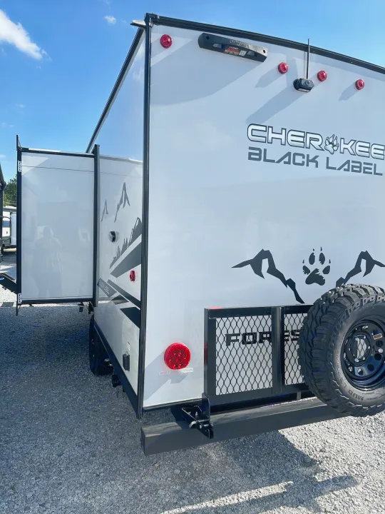Rear view of a white Cherokee Black Label travel trailer with a side open. Ideal for your next RV rental adventure.. Forest River Cherokee Wolf Pup 2025