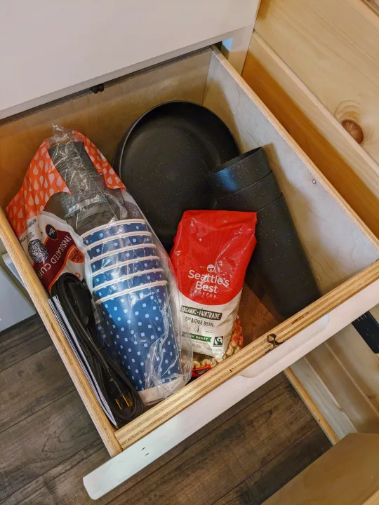 RV rental kitchen drawer stocked with Seattle's Best coffee, insulated cups, paper cups, and a cooking pan.. Sprinter Mercedes 2018