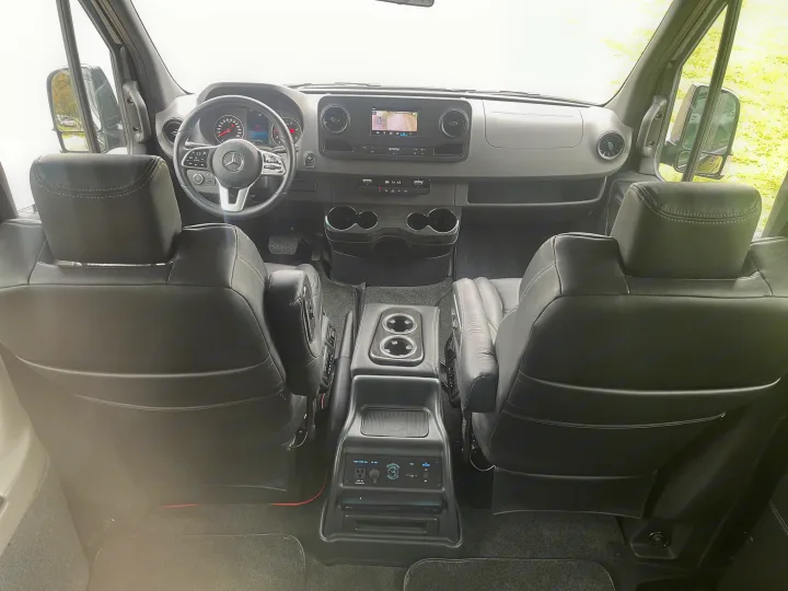 Inside this RV rental: Mercedes-Benz cockpit with modern dash, plush captain's chairs, and practical central console. Perfect for journeys.. Mercedes Benz Sprinter 3500 2022