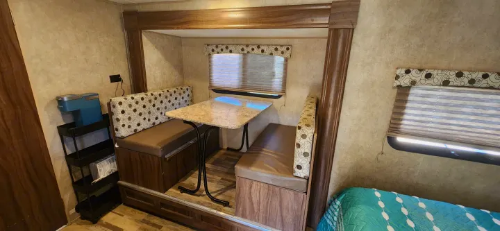 RV rental interior: Comfortable dinette with a table, padded benches, windows, and a coffee maker setup.. Coachmen Clipper 2018