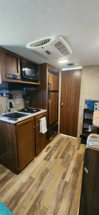 Explore this RV rental's cozy kitchen: microwave, stove, sink, fridge, and wood-look flooring for your adventures.. Coachmen Clipper 2018