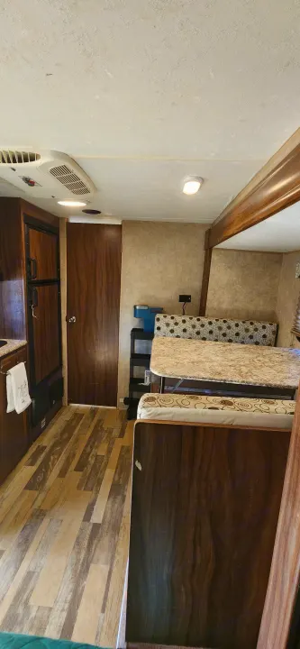 This RV rental interior features a functional dinette with patterned cushions, a light-colored table, wood-look. Coachmen Clipper 2018