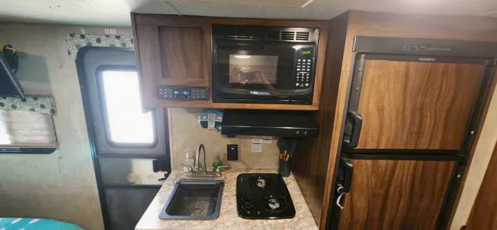Compact RV rental kitchen with microwave, sink, stovetop, and Dometic fridge for convenient travel.. Coachmen Clipper 2018