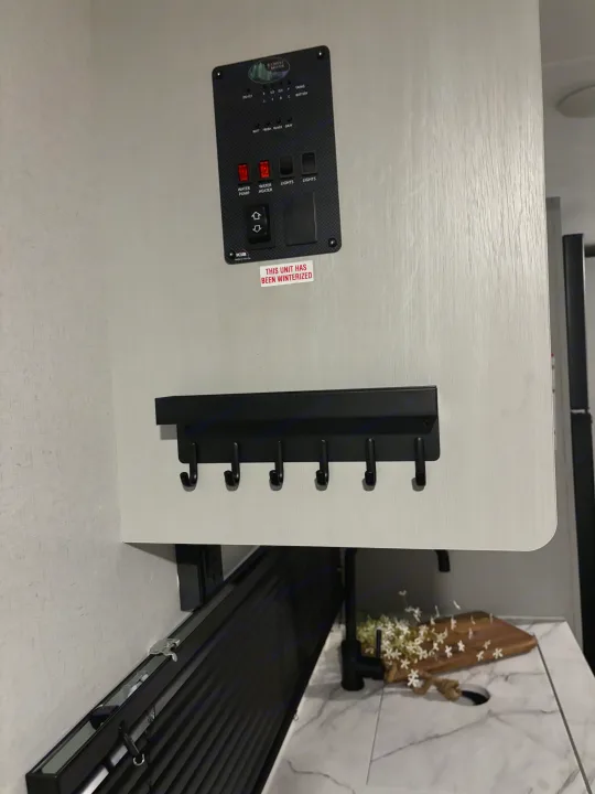 RV rental interior showing a control panel, "winterized" notice, key hooks, and a modern kitchen with sink.. Forest River Wildwood 2021