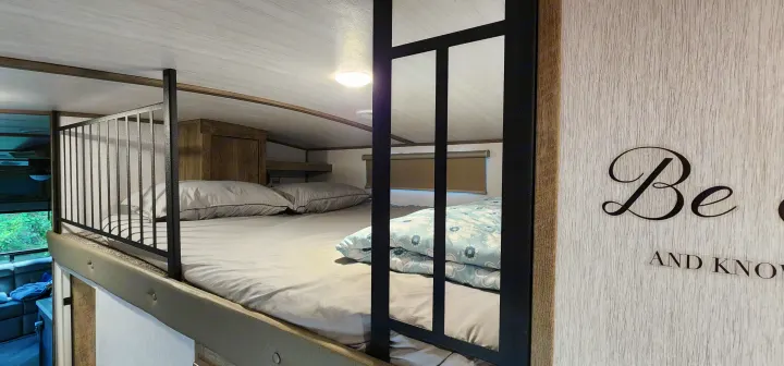 Cozy RV rental loft featuring bunk beds with bedding, a decorative rail, and a light fixture for comfortable stays.. Forest River Hemisphere 2022