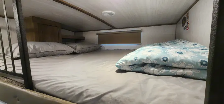 Cozy RV rental bunk bed with comfortable grey bedding and a blue floral comforter.. Forest River Hemisphere 2022