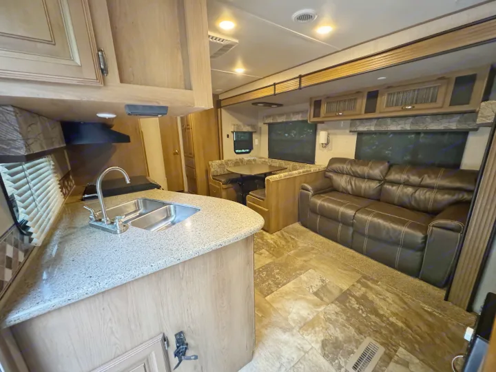 An inviting RV rental interior featuring a modern kitchen, comfy leather sofa, and built-in dinette for travelers.. Crossroads RV Cruiser Aire 2016