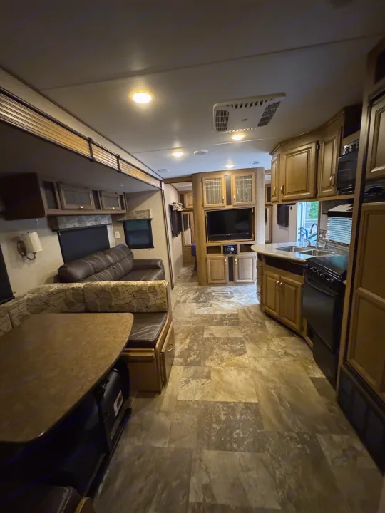 RV rental interior with a modern kitchen, dining nook, and comfortable lounge area featuring a sofa and entertainment center.. Crossroads RV Cruiser Aire 2016