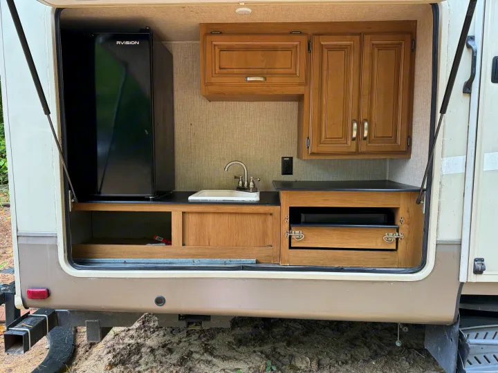 Explore this RV rental's outdoor kitchen with a fridge, sink, countertop, and storage. Perfect for camping adventures.. Crossroads RV Cruiser Aire 2016