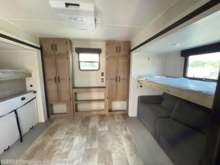 Spacious RV rental interior features wood-look floors, bunk beds, a sofa, and light wood storage cabinets.. Forest River Palomino Puma 2022