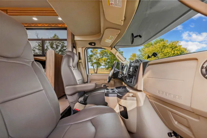 RV rental interior: Front cabin shows swiveling driver & passenger seats, steering wheel, and dashboard, ready for a journey.. Entegra Coach Odyssey 2020