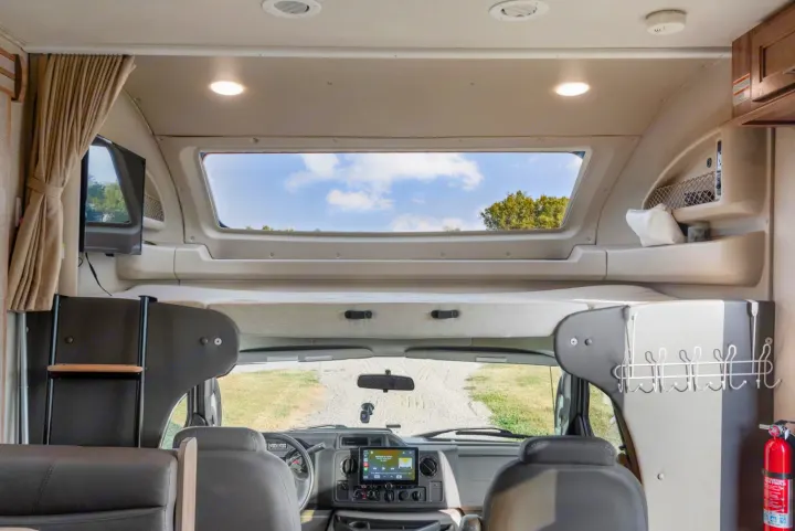 RV rental interior: front cab, overhead bunk, and large skylight revealing the sky and trees.. Entegra Coach Odyssey 2020