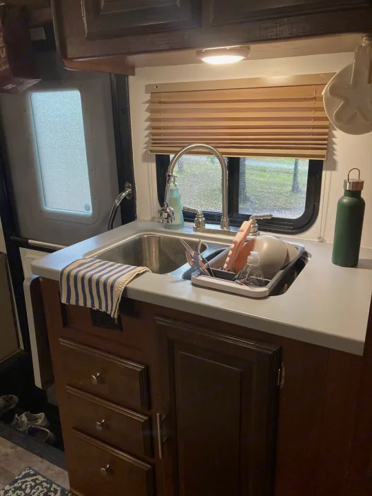 RV rental kitchen: Sink with dishes drying, striped towel, green water bottle, and outdoor view.. Georgetown GT3 2016