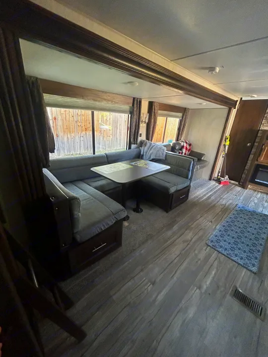 An RV rental's inviting dinette and living area, featuring large windows and wood-look flooring.. Forest River Cherokee Grey Wolf 2019