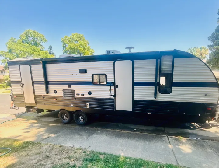 Modern travel trailer, possibly for RV rental, parked on a driveway with doors open on a sunny day.. Forest River Cherokee Grey Wolf 2019