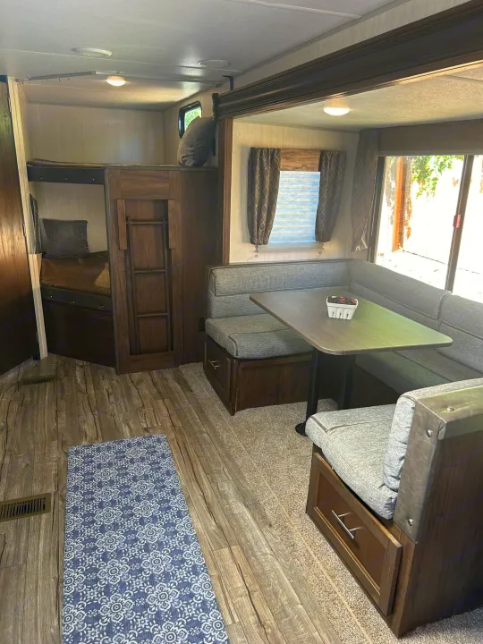 RV rental interior: cozy dinette, bunk beds for extra sleeping, and wood-look flooring. Perfect for family trips.. Forest River Cherokee Grey Wolf 2019