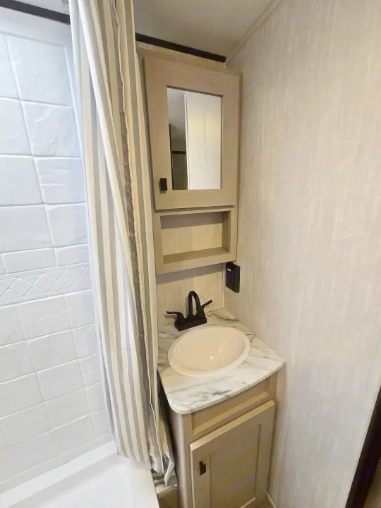Modern RV rental bathroom with a spacious shower, vanity sink, mirror cabinet, and light wood cabinetry.. Coachmen Apex Nano 2024