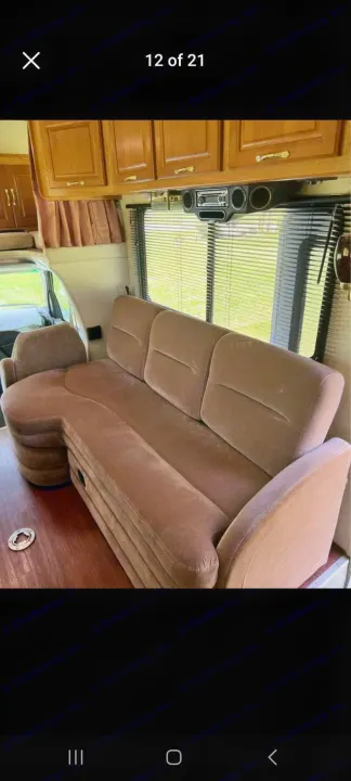 Experience comfort in this RV rental's living area: a plush brown sofa, wood cabinetry, and large windows for scenic views.. Coachmen Santara 1998