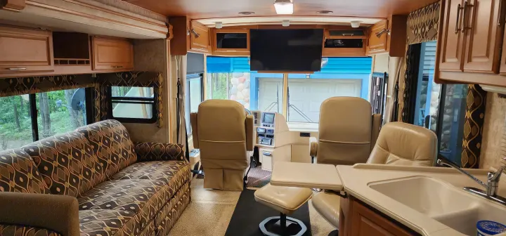 Experience comfort in this RV rental! Interior view showing a cozy sofa, kitchen, and driver's area with captain's chairs, ideal for travel.. Winnebago Journey 2006