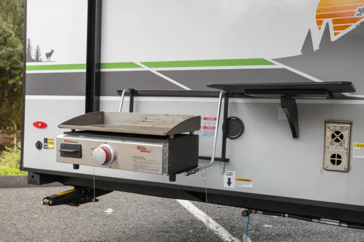 RV rental featuring a convenient outdoor cooking setup: a mounted griddle and side table for delicious campsite meals.. No Boundaries 19 2023