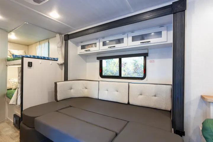 Spacious RV rental interior features a convertible bench seat, bunk beds, and overhead storage, ideal for families.. No Boundaries 19 2023