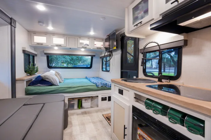 Inside this RV rental: a compact yet complete living space with a comfy bed, kitchen, and seating area.. No Boundaries 19 2023