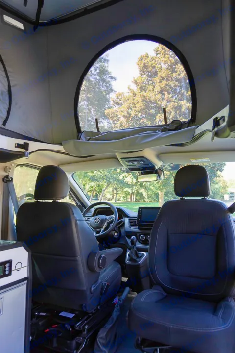 RV rental interior: Front cockpit view with swiveling seats, dashboard, and a large pop-top window overlooking trees.. HANROAD TREK 5 2026