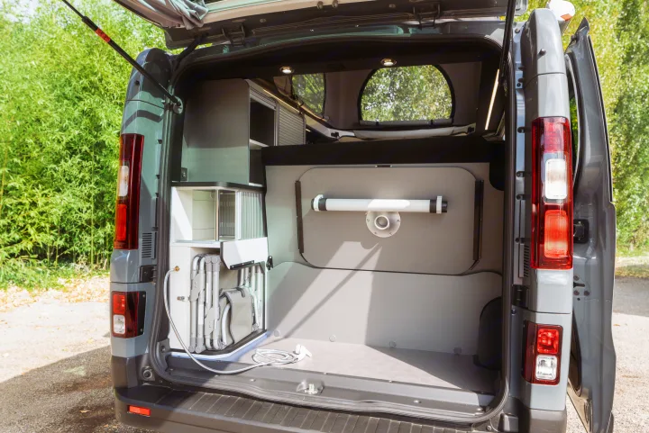 Inside an RV rental: Rear storage of a camper van with built-in kitchen, chairs, and outdoor shower setup.. HANROAD TREK 5 2026