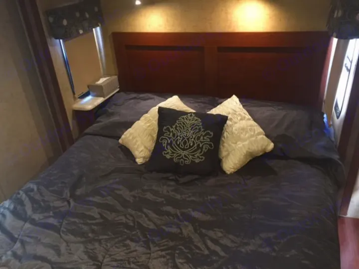 RV rental interior: Comfortable bedroom with dark bedding, wood headboard, and nightstand. A perfect sleeping area.. Forest River Forester 2016