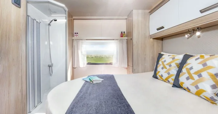 Comfortable RV rental interior: bedroom with bed, scenic window view, and compact shower. Ideal for travel.. Auto-Trail F74 2025