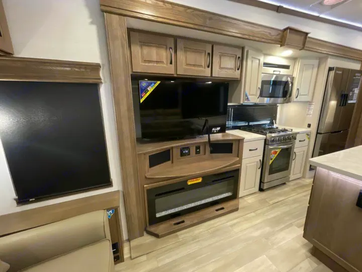 This RV rental features a modern living area with TV, fireplace, and a full kitchen, including oven, microwave, and fridge.. Alliance RV Paradigm 2024