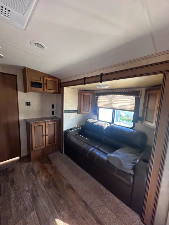 Cozy RV rental living area with a reclining sofa, entertainment center, and wood-look flooring.. Cruiser RV Shadow Cruiser 2016