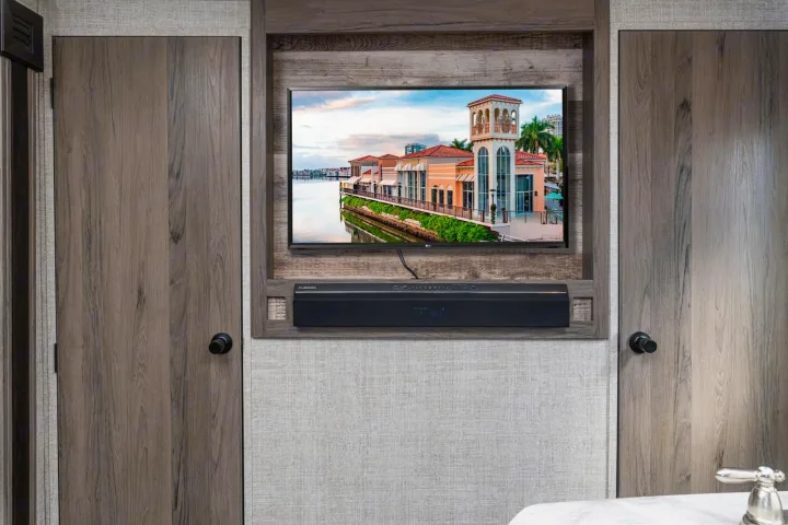 RV rental interior features a modern entertainment setup: TV, soundbar, and two elegant wooden doors. Relax and enjoy.. Gulf Stream Ameri-Lite 2024
