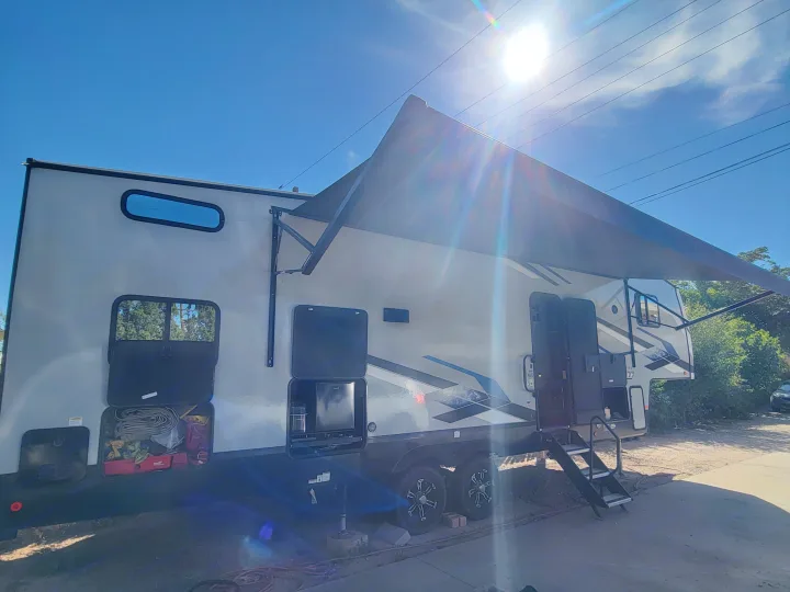 This RV rental toy hauler, with its awning extended and compartments open, is set for your next outdoor adventure.. Forest River Cherokee Arctic Wolf 2023
