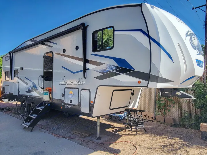 Modern Arctic Wolf fifth-wheel RV camper, great for an RV rental. Steps down, jacks deployed, ready for your next trip.. Forest River Cherokee Arctic Wolf 2023