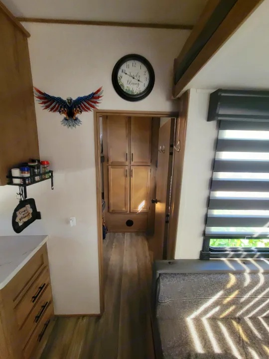 Inside an RV rental: kitchen counter, wall decor, hall to storage, and a sunlit sitting area by blinds.. Forest River Cherokee Arctic Wolf 2023