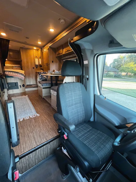 Step inside this RV rental, showcasing the driver's seat, dining area, and cozy bedroom in a modern camper van.. Forest River Coachmen Prism 2016