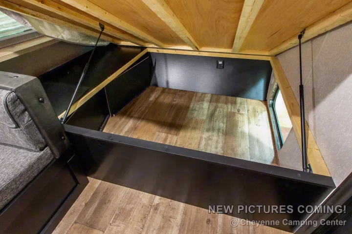 Discover practical under-bed storage in this RV rental, featuring durable wood-look flooring and gas strut support. Ideal for camper trips.. Forest River Cherokee Wolf Pup Black Label 2022