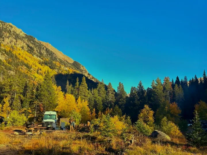 Autumn mountain camping with an RV rental amidst golden trees and clear skies. Perfect nature escape.. Mercedes-Benz Sprinter 2021