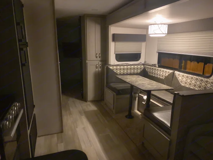 Experience comfort in this RV rental's modern interior, featuring a cozy dinette with patterned seating, ample storage, and laminate floors.. Forest River Tracer 2021