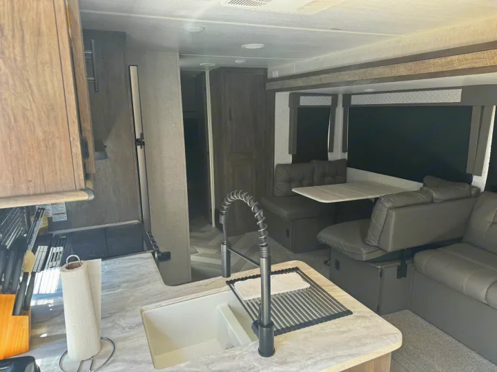 Clean RV rental interior: kitchen with sink & high faucet, dining booth, and comfortable living space.. Forest River Other 2021