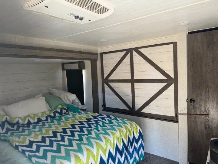 Inside a comfortable RV rental bedroom featuring a bed with a vibrant chevron comforter and decorative wall panels.. Forest River Other 2021