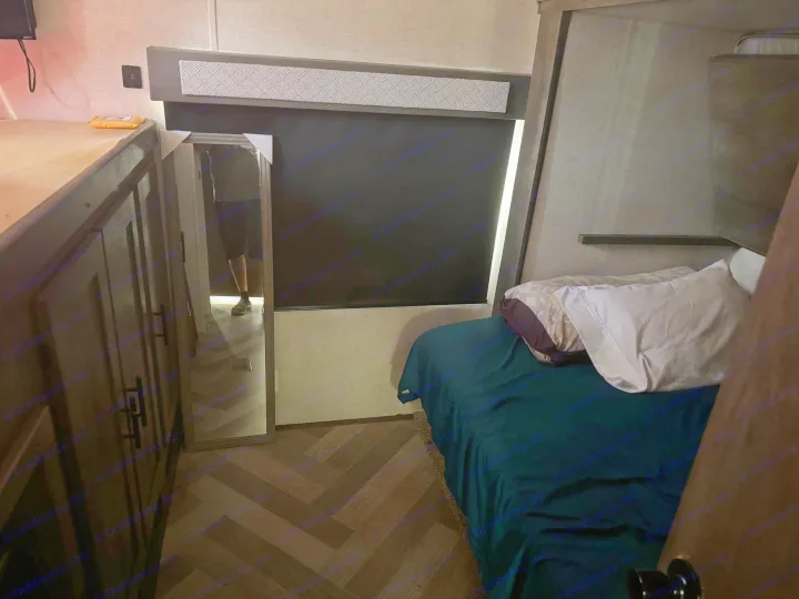 Inside this RV rental: compact bedroom featuring a cozy lower bed, bunk area, mirror, and built-in storage.. Forest River Other 2021