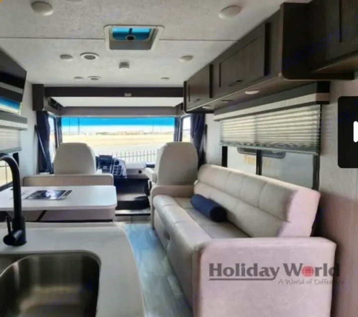 Modern RV rental interior showing living area, kitchen sink, sofa, & dinette. Spacious layout for travel.. Forest River Coachmen Pursuit 2023