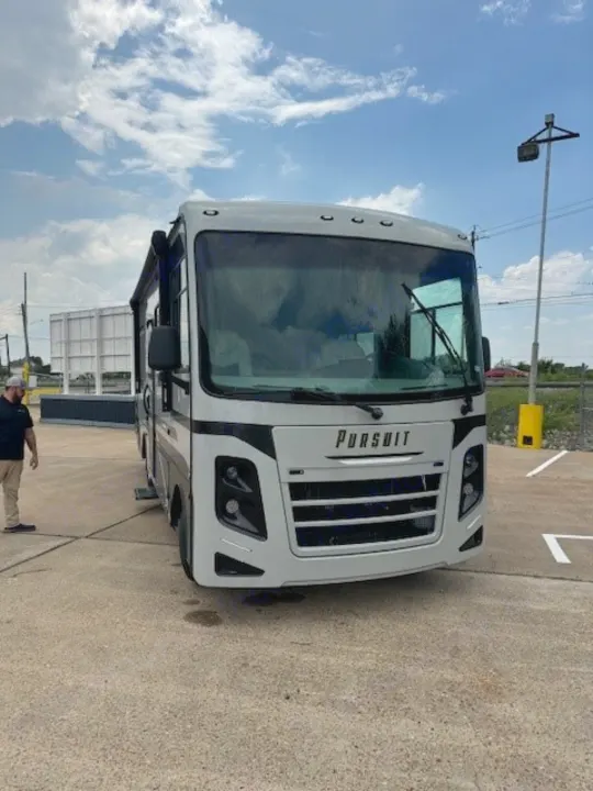 Front view of a white Pursuit motorhome RV rental, parked on asphalt under a cloudy sky.. Forest River Coachmen Pursuit 2023