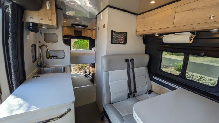 Spacious RV rental interior with a kitchen, seating area, and a bed in the rear, perfect for mobile living.. Airstream Rangeline 2023