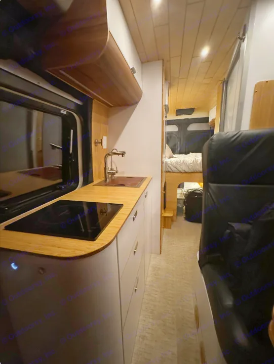 Modern RV rental interior featuring a bamboo kitchen with sink/cooktop and a cozy rear bed area, perfect for travel.. Noovo Pop 2024