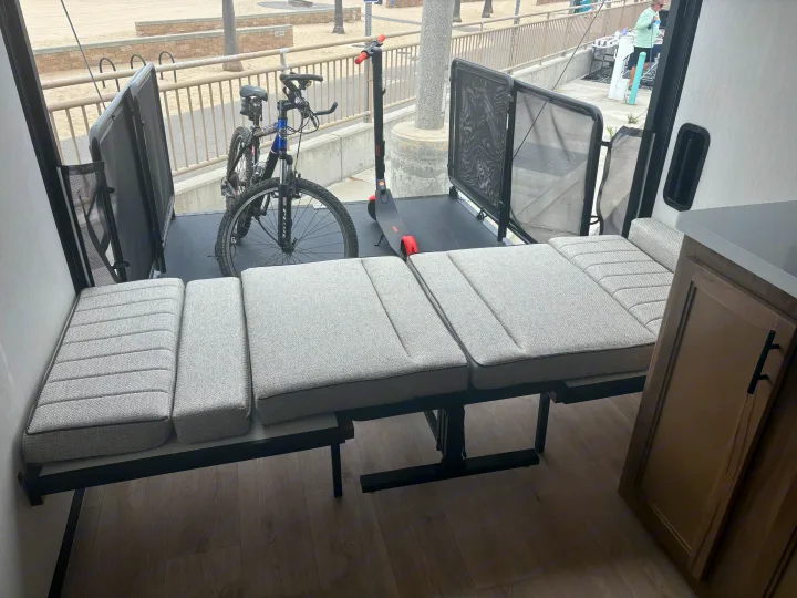 RV rental toy hauler with versatile interior: sofa converts to bed, bikes & scooter on the outdoor patio overlooking the beach.. Forest River Wolf Pup 2025